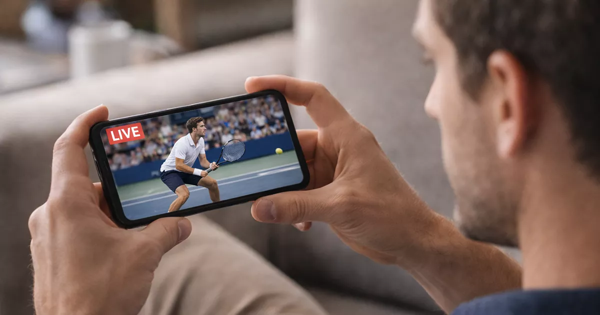 Aficionado siguiendo partido de tenis en directo desde su móvil
