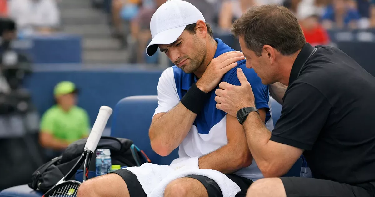 Tenista sentado en el banquillo recibiendo atención médica