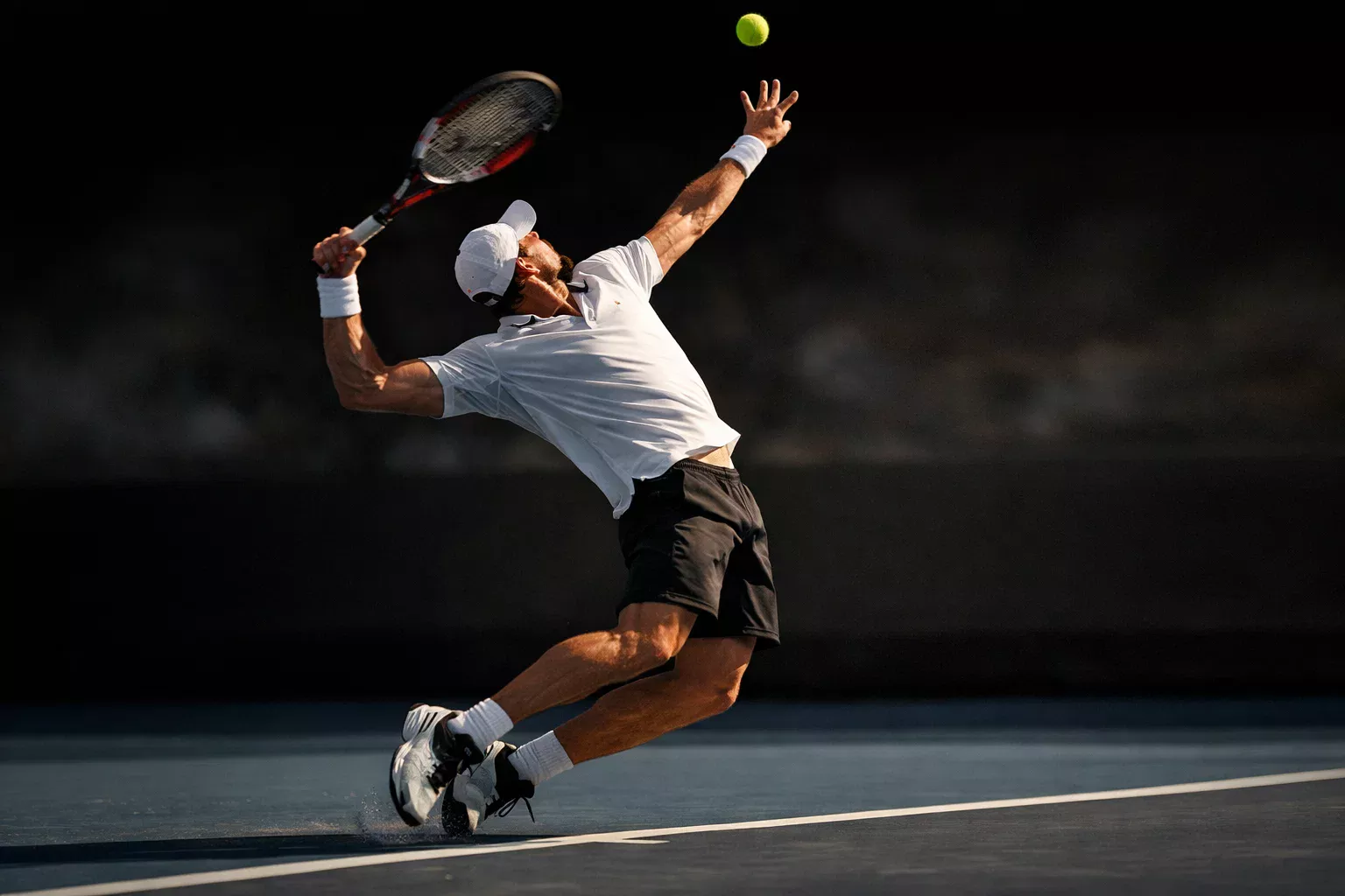 Tenista ejecutando un saque potente en pista de tenis profesional
